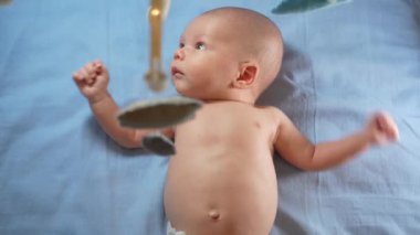 Çocuk, bebek beşiğinin üzerinde dönen el yapımı yumuşak oyuncaklarla müzikal bebek hareketine bakıyor..