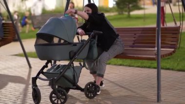 Elinde bebek arabası olan annem bir apartmanın avlusunda salıncakta oturuyor.