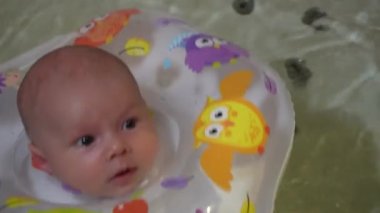 Bir çocuk şişme halkalı bir küvette banyo yapıyor. Küçük bir çocuk banyoda yüzüyor..