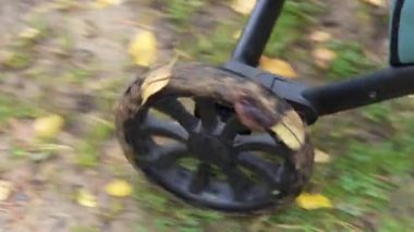 Sonbaharda yaprakların ve su birikintilerinin üzerinde giden bir bebek arabasının tekerlerinin yakın çekimi.