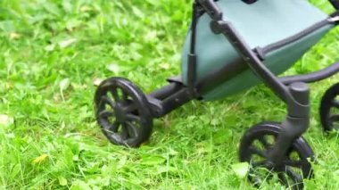 Sonbaharda yaprakların ve su birikintilerinin üzerinde giden bir bebek arabasının tekerlerinin yakın çekimi.