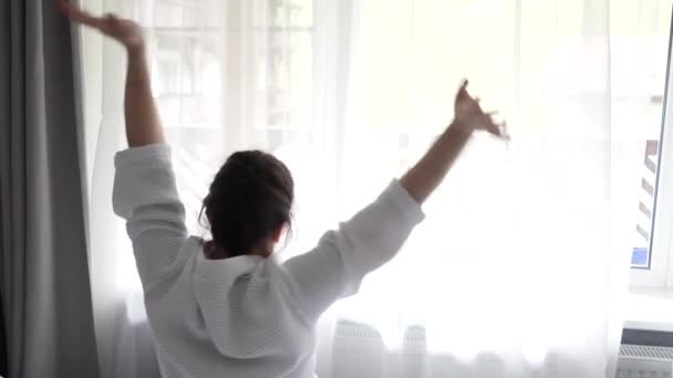 Sempatik Bir Kız Sabah Uyandığında Pencerenin Yanındaki Yatağın Üzerinde Ellerini — Stok video