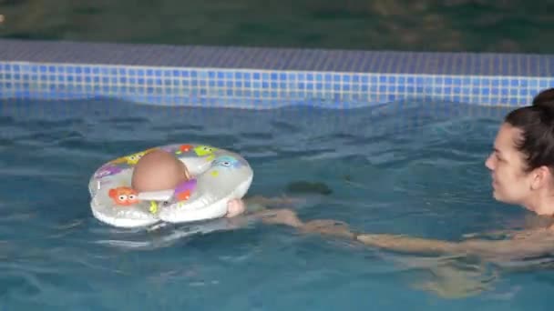 一个带着孩子的年轻妈妈在游泳池里游泳 — 图库视频影像