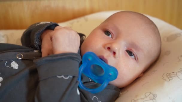 Little cute baby with blue pacifier in mouth, close-up portrait — Stock Video