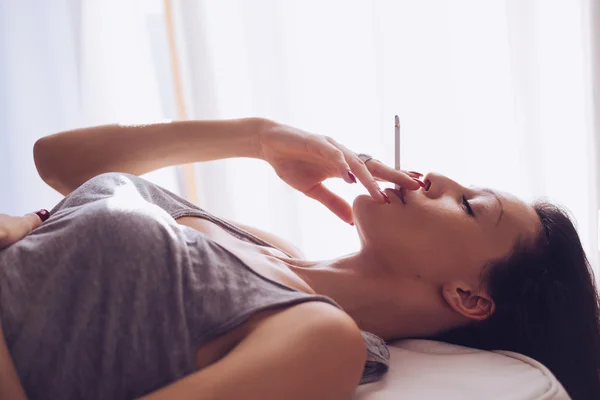 Smoking girl lying by the window — Stock Photo, Image