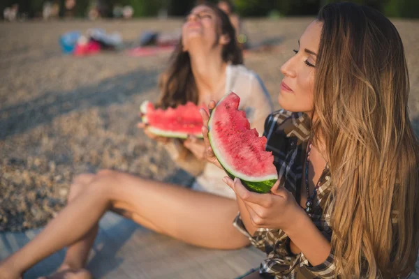 Fidanzate ridendo e mangiando anguria sulla spiaggia — Foto Stock