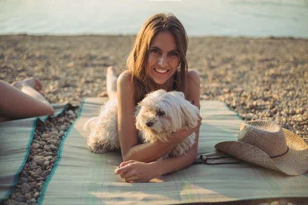 Девушка с собакой лежит на пляже и улыбается — стоковое фото