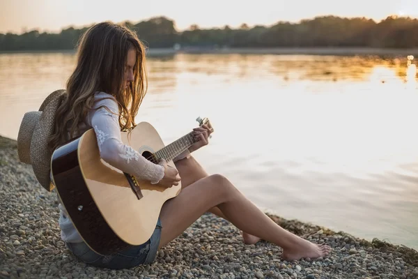 Mädchen spielt Gitarre während sie am Strand sitzt — Stockfoto