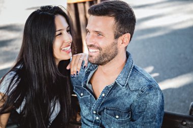 Çift oturma ve bir bankta gülümseyen