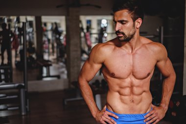 Spor salonunda duran ve tarafına bakarak yorgun adam