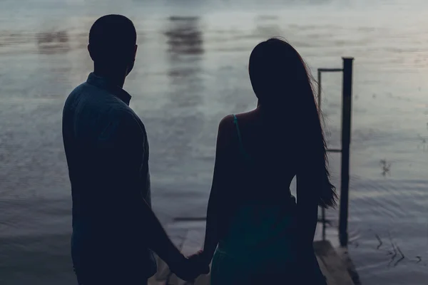 Pareja cogida de la mano y mirando al atardecer — Foto de Stock