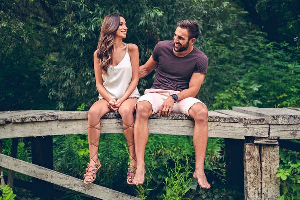 Pareja sentada en el muelle y riendo — Foto de Stock