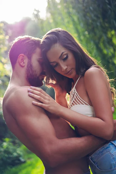 Uomo gentilmente abbracciando la sua ragazza con il sole dietro — Foto Stock