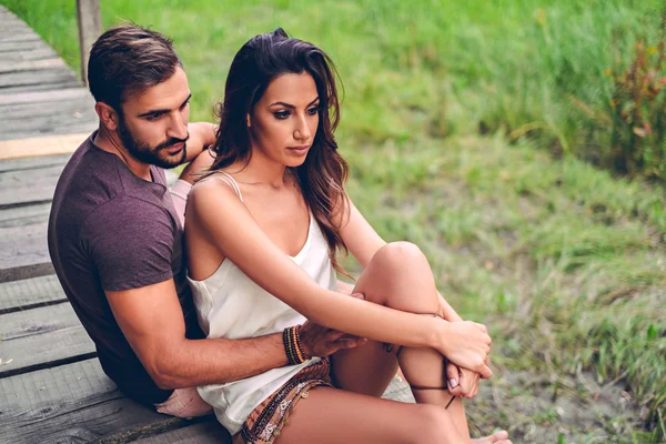 Casal sentado no cais parecendo preocupado — Fotografia de Stock