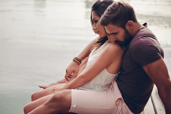 Pareja abrazándose junto al río y mirando hacia el agua — Foto de Stock