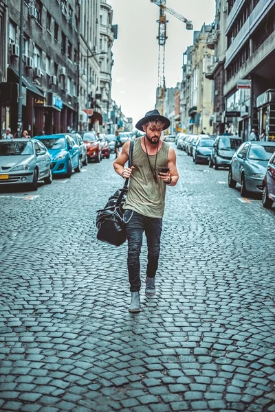 Hipster περπατώντας στον δρόμο και ψάχνουν στο τηλέφωνο — Φωτογραφία Αρχείου