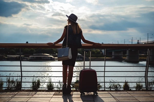 Menina com bagagem à espera junto ao rio — Fotografia de Stock