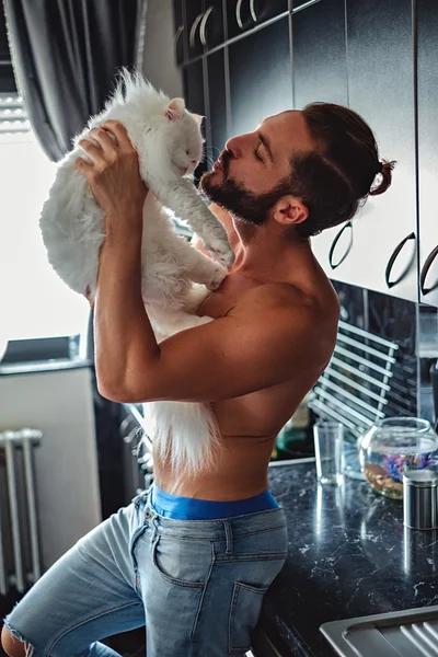 Man kissing his pet cat in the kitchen — Stock Photo, Image