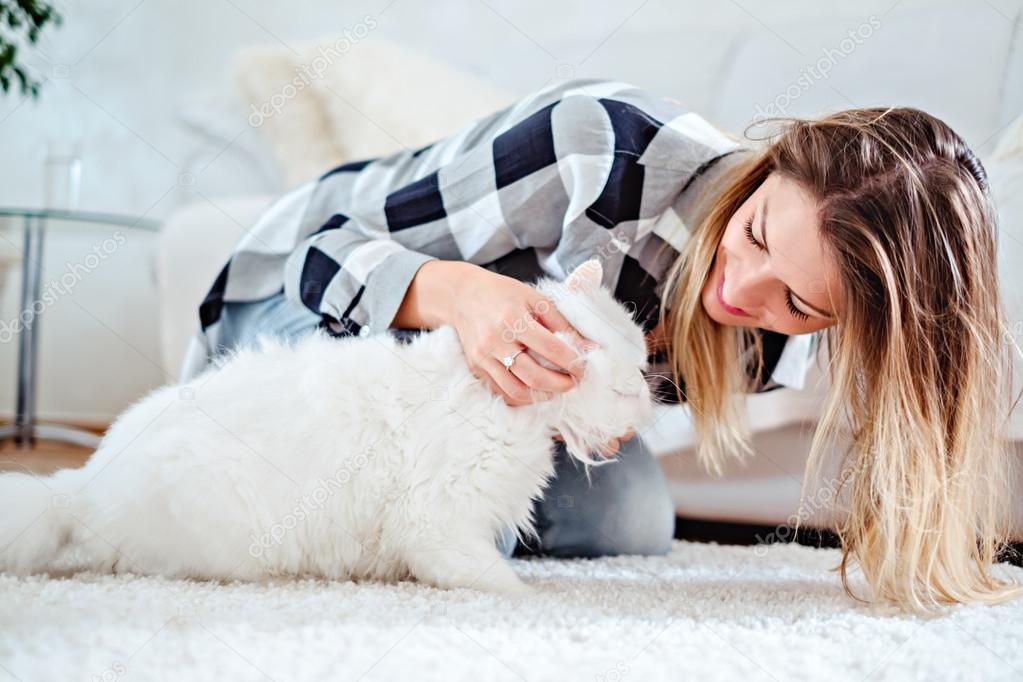 Girl playing with her white cat