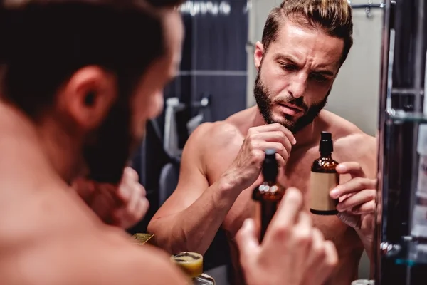 Hipster man holding bottle in the bathroom — Stock Photo, Image