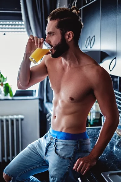 Półnagi człowiek pije sok w kuchni — Zdjęcie stockowe