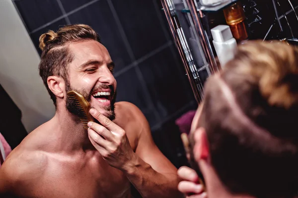 Мужчина расчесывает бороду в ванной — стоковое фото