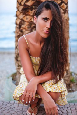 Güzel kız palmiye ağacı önünde diz çökmüş