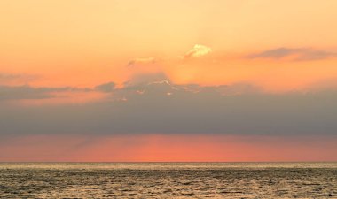 Gün batımında sakin denizin üzerinde gökyüzü turuncudur. Denizin üzerinde gün batımı.