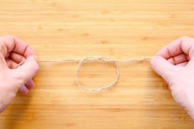 İnsan eli, ahşap bir arka planda ipe düğüm atar. Arkadaşlık ve aşk büyüsü kavramı.