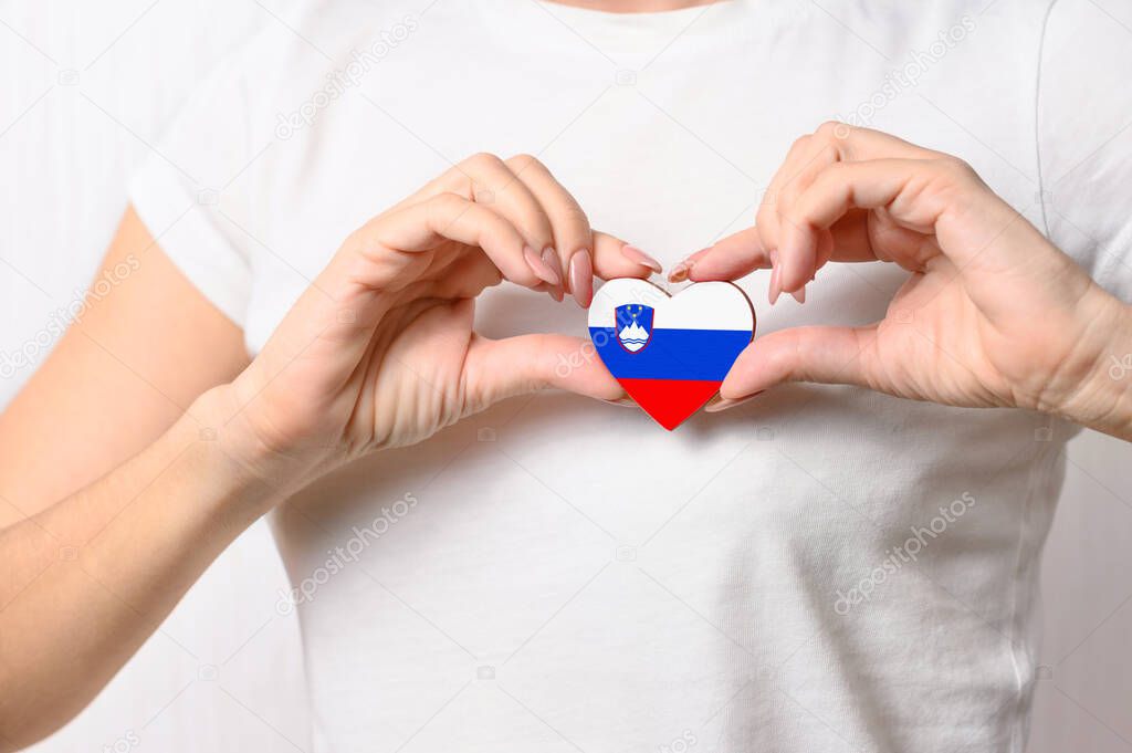 Love Slovenia. A girl holds a heart in the form of the flag of Slovenia on her chest. Slovenian concept of patriotism