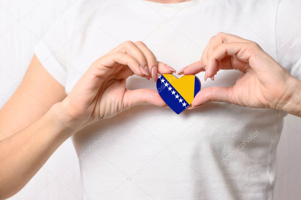 Love Bosnia and Herzegovina. The girl holds a heart in the form of the flag of Bosnia and Herzegovina on her chest. Bosnian patriotism concept