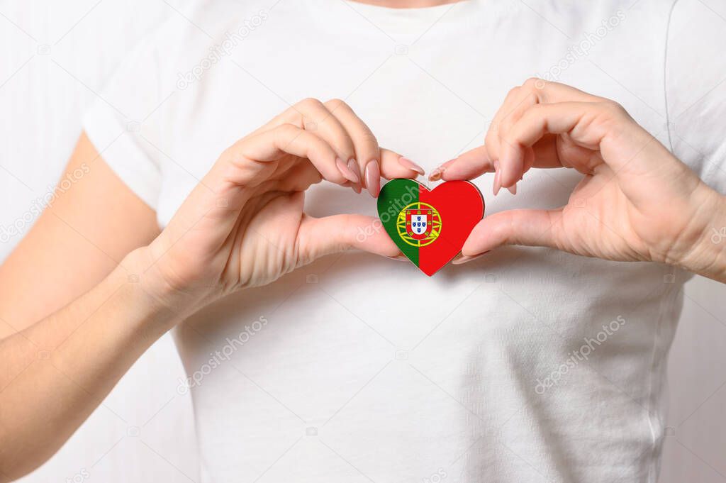 Love Portugal. The girl holds a heart in the form of the flag of Portugal on her chest. Portuguese patriotism concept