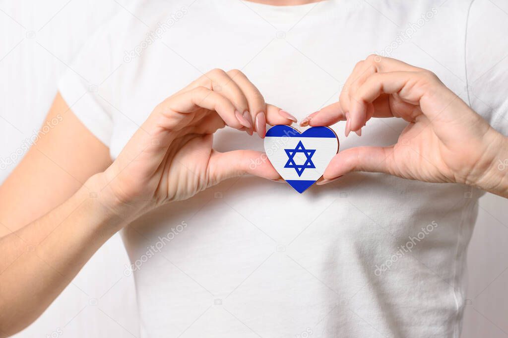 Love Israel. The girl holds a heart in the form of the flag of Israel on her chest. Israeli patriotism concept