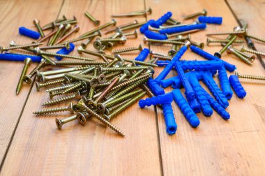 Bir sürü mavi perdeler ve ahşap bir masada kesilen kendi kendine dokunan vidalar. Önplanda seçici odaklanma.