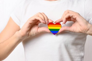 LGBT ilişki konsepti. Kız göğsünde LGBT bayrağı şeklinde bir kalp taşıyor..