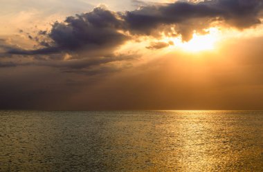 Karadeniz yüzeyinde altın gün batımı ve dramatik gökyüzü.