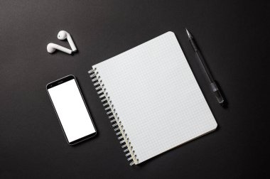 İş konferansı için konular ya da siyah arka plan hakkında online dersler. Eşyalar çapraz istiflenmiş. Reklamınız için boş beyaz ekranlı bir defter, kalem ve akıllı telefon açın. Yukarıdan görüntüle.