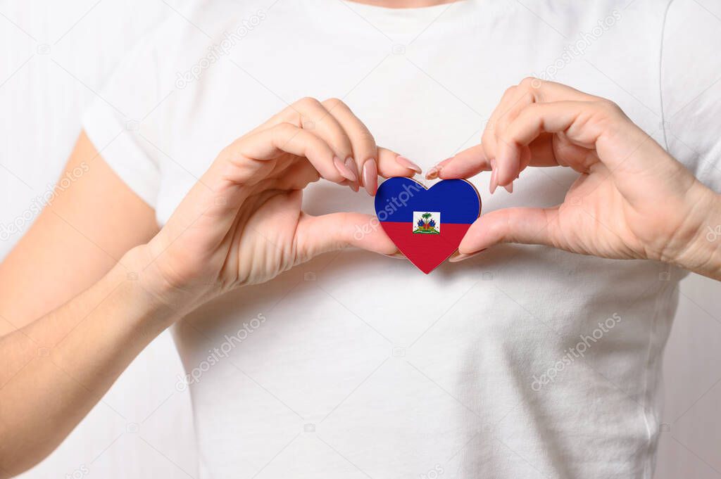 Flag of Haiti in the shape of a heart in the hands of a girl. Love Haiti. The concept of patriotism