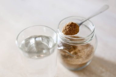 Bir kaşık saf suyun yanında, bir kaşık içindeki besin bitkisinin genel görüntüsü. Seçici olarak gıda katkı maddesine odaklan. Sağlıklı gıda konsepti.