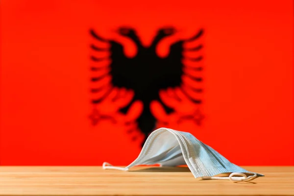Uma Máscara Médica Está Sobre Mesa Contra Fundo Bandeira Albânia — Fotografia de Stock