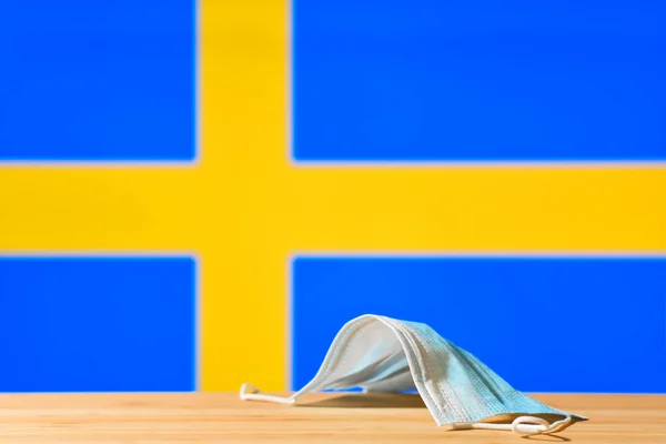 スウェーデンの国旗を背景に医療用マスクがテーブルの上に置かれている パンデミック時のスウェーデンの住民と観光客のための強制マスク制度の概念 — ストック写真