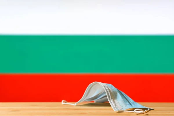 Uma Máscara Médica Está Sobre Mesa Contra Fundo Bandeira Bulgária — Fotografia de Stock