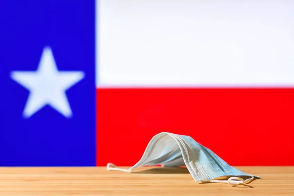 テキサスの国旗を背景に医療用マスクがテーブルの上に置かれている パンデミックの間 テキサス州の住民と観光客のための強制マスク制度の概念 — ストック写真