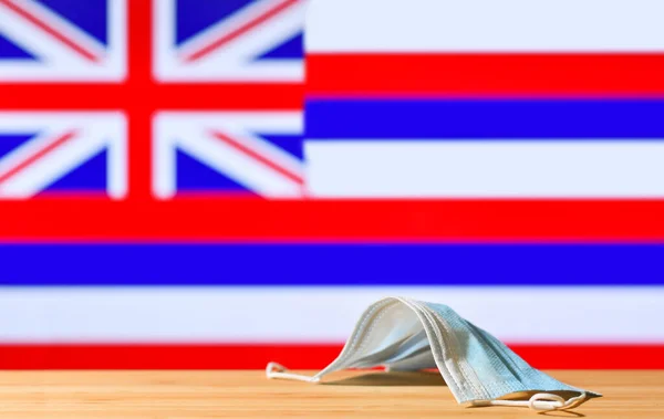 Uma Máscara Médica Está Sobre Mesa Contra Fundo Bandeira Havaí — Fotografia de Stock