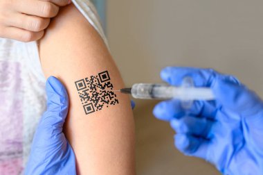 The concept of vaccination of the population and the assignment of a personal code. Electronic code on a man's hand and a syringe with a vaccine.