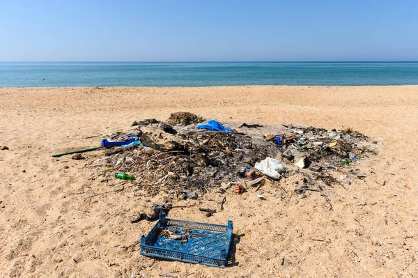 A large pile of rubbish on the wide sandy shore of the Black Sea.