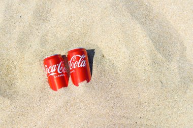 Anapa, Rusya - Temmuz 2021: İki kutu lezzetli ve soğuk Coca-Cola kumsalda yatıyor.