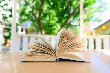 Açık olan kitap yaz köşkünde yatıyor. Keskinliğin sığ derinliği.