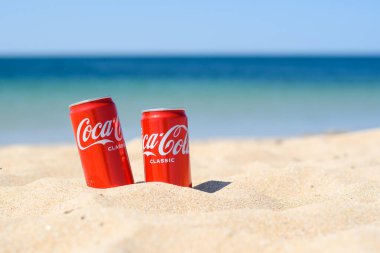 Anapa, Rusya - Temmuz 2021: İki kırmızı Coca-Cola kutusu kumsalda gömülü.