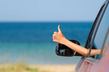Arabayla başarılı bir tatil konsepti. Kumsaldaki arabanın camından elini kaldır..